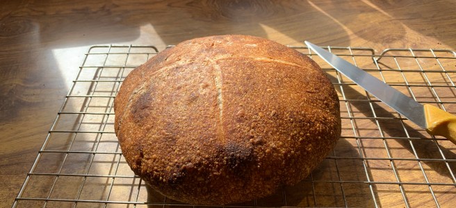 White loaf on a cooling rack with a knife for scale